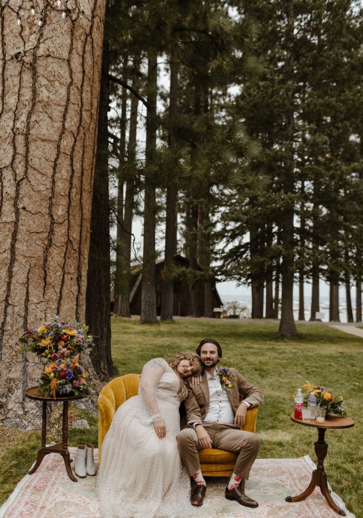 Wedding couple sitting on couch outside at valhalla in Lake Tahoe with pine trees in background