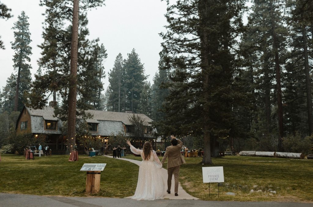 Wedding couple waving to wedding guests as they walk along pathway into reception at valhalla in Lake Tahoe