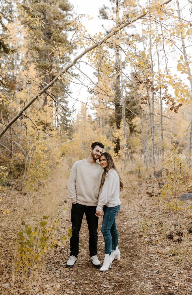 couple hugging and smiling under orange aspens in lake tahoe