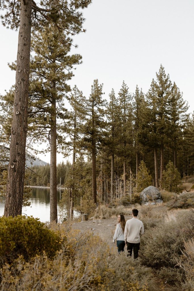 couple walking on a trail in lake tahoe overlooking the lake for their engagement photos