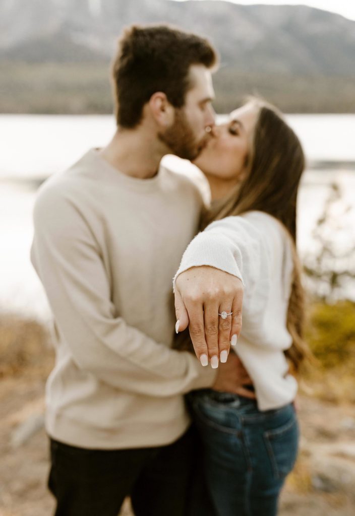 couple kissing and showing off engagement ring 