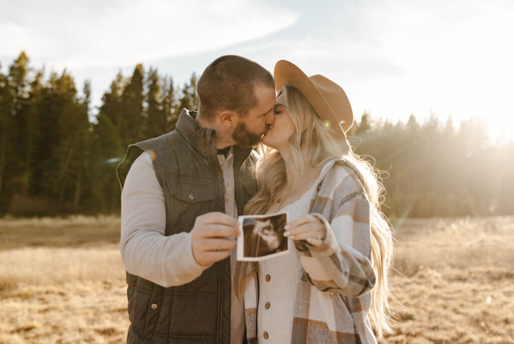couple holding ultrasound and kissing