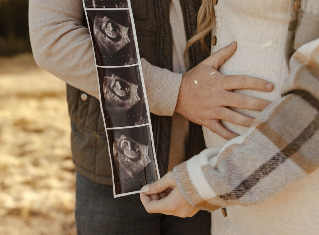 couple holding ultrasound and holding belly