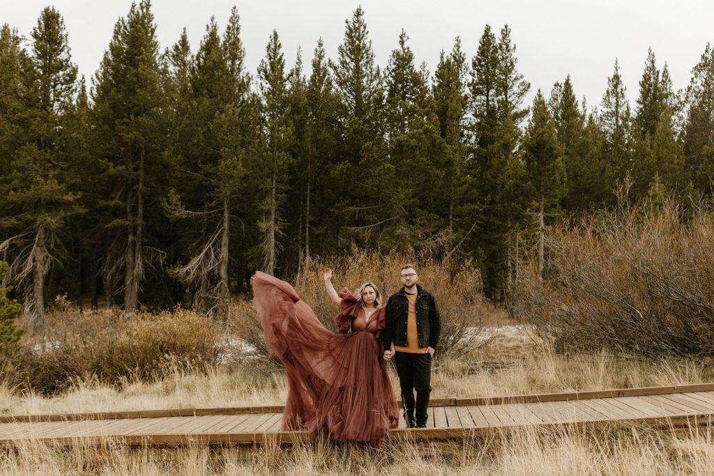 woman playing with her maroon dress  with fiance in a meadow in lake tahoe