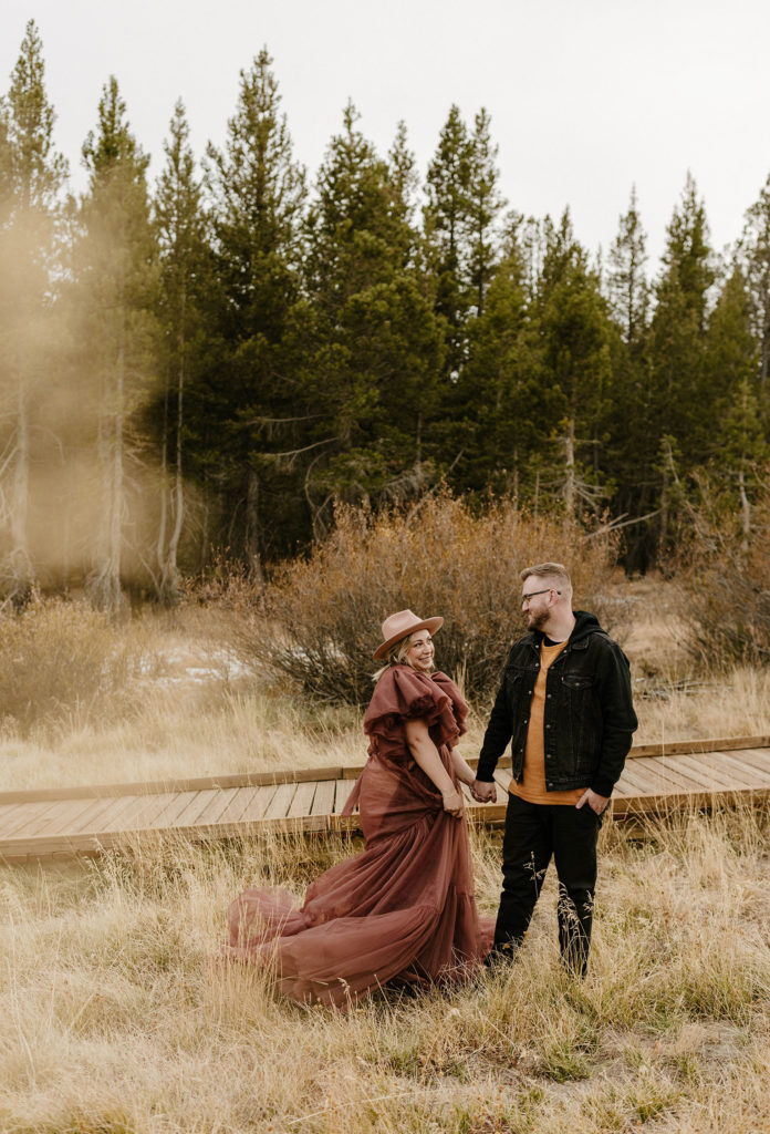 couple smiling in meadow in lake tahoe for their engagement photos