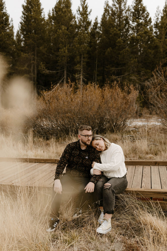 couple sitting on a path in a meadow in lake tahoe for their engagement photos