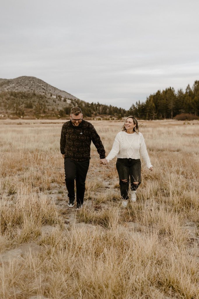 couple walking in a meadow in lake tahoe for their engagement photos