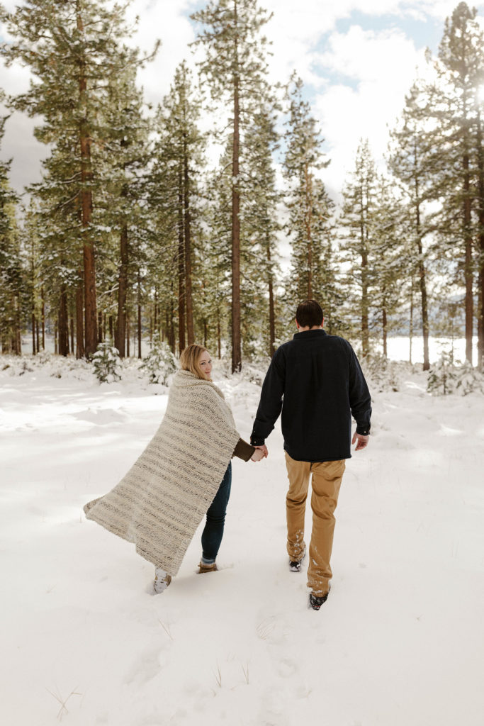 couple walking through the snow for their winter lake tahoe engagements