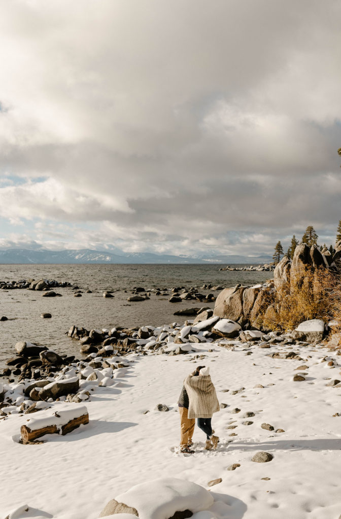 couple hugging on the beach in lake tahoe in the winter