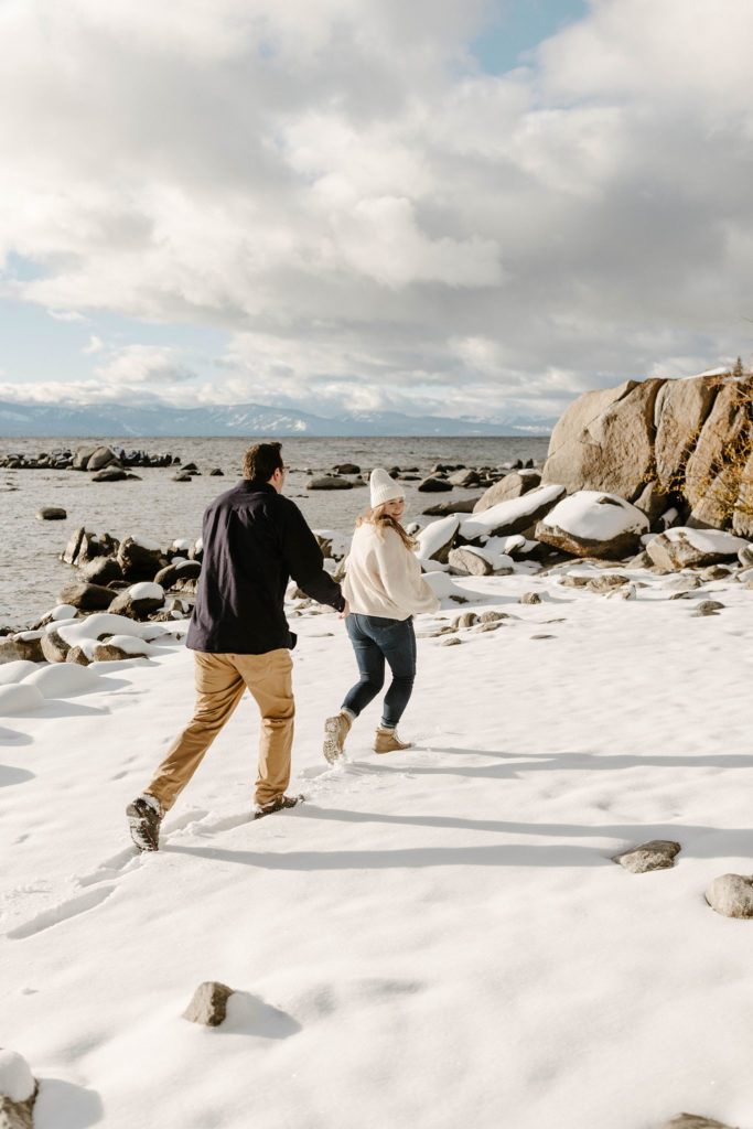 couple running on the beach in lake tahoe in the winter