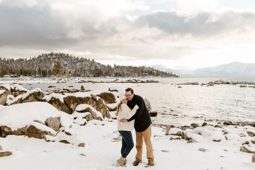 couple hugging on the beach for their winter lake tahoe engagements