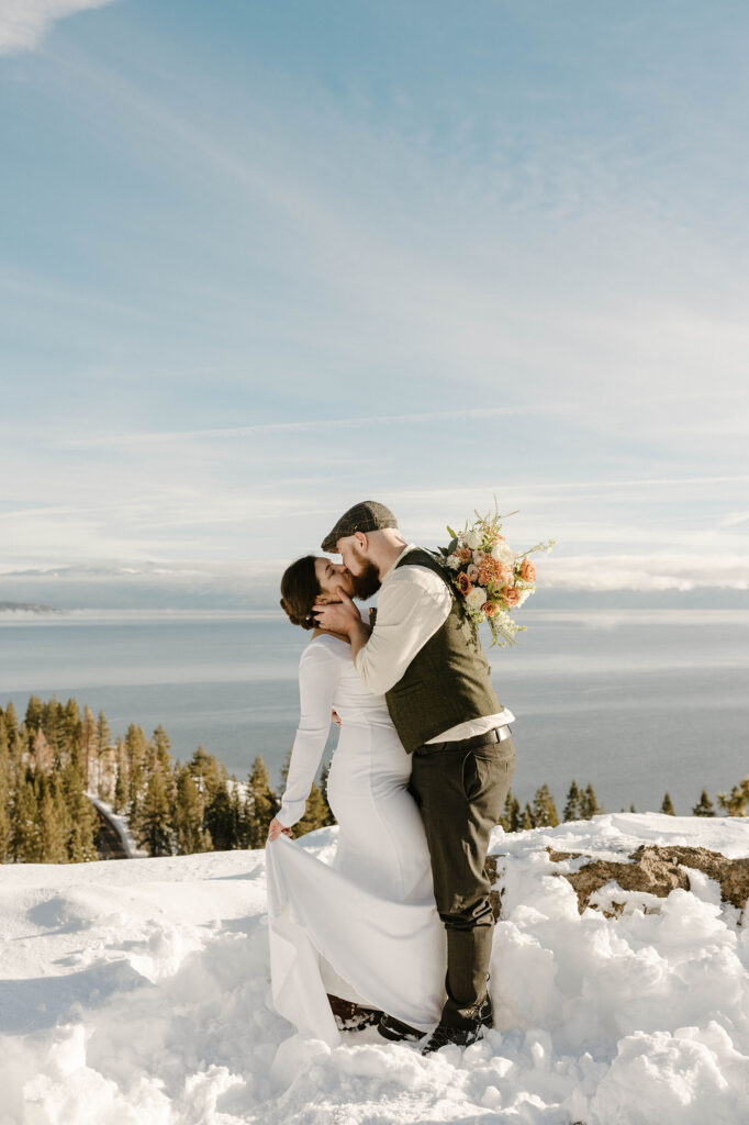 elopement couple kissing in the snow overlooking lake tahoe
