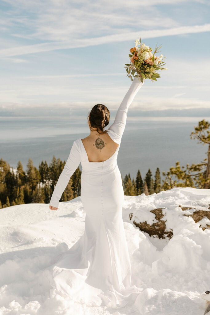 bride holding her bouquet in the air overlooking lake tahoe