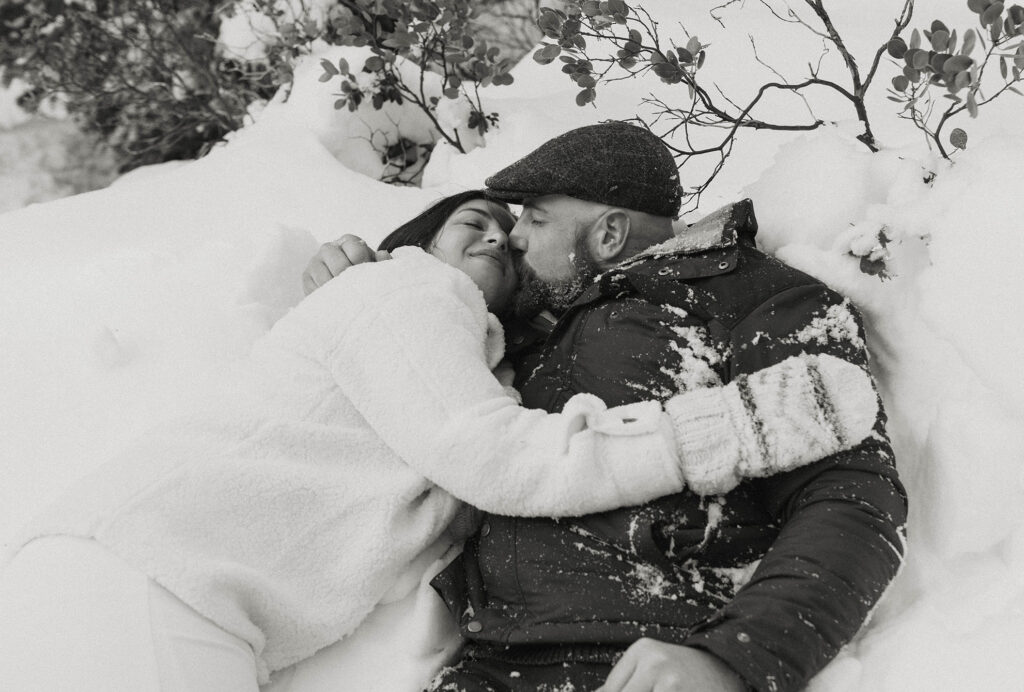 elopement couple laying in the snow kissing in lake tahoe