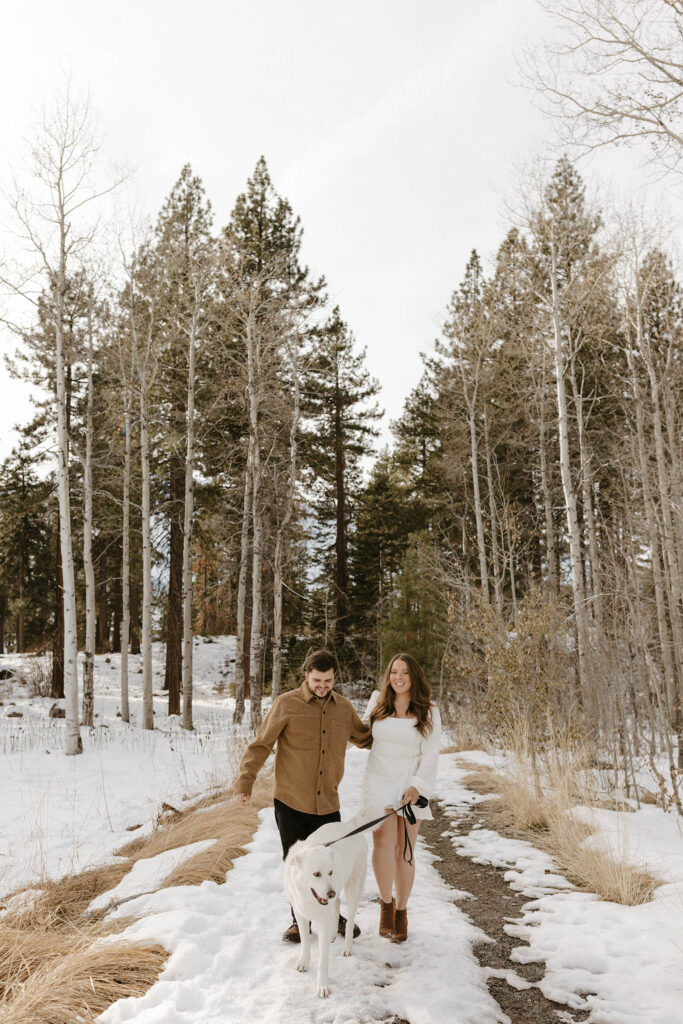 engagement couple walking in the snow with their dog in lake tahoe