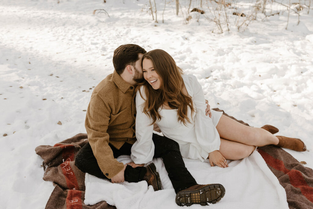 couple sitting on a blanket in the snow