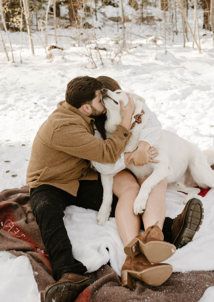 couple hugging their dog in the snow