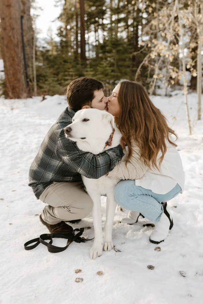 couple kissing with their dog in the snow in lake tahoe