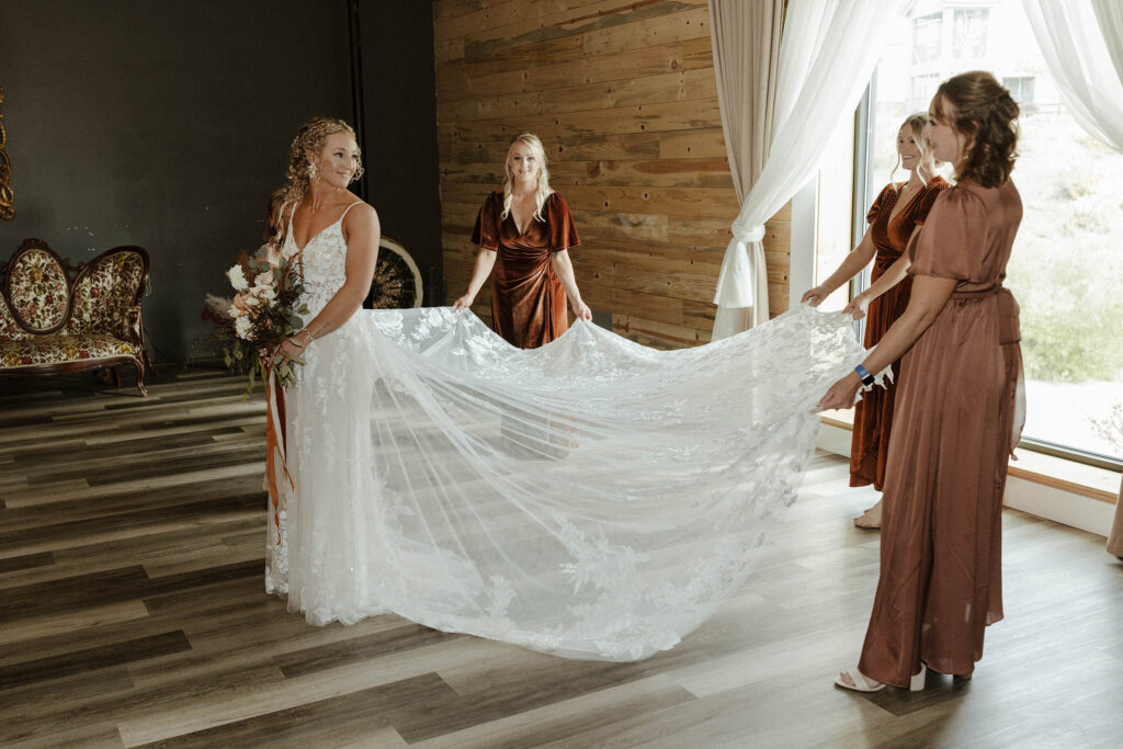 bridesmaids holding the brides dress and fanning it out