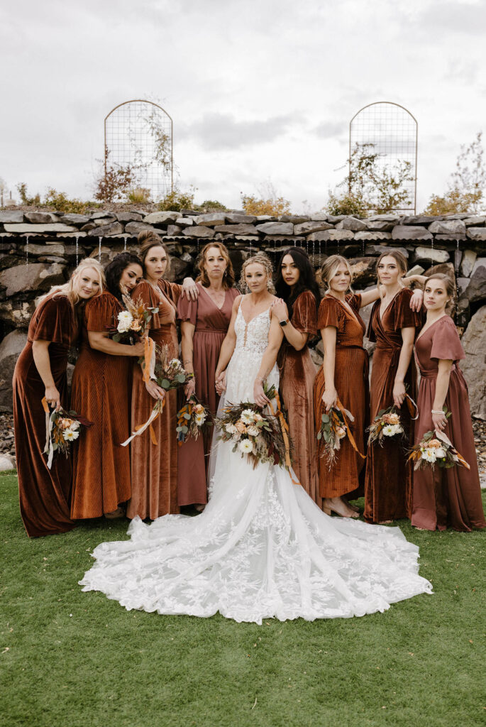 burgundy and burnt orange bridesmaids dresses while they pose at the camera