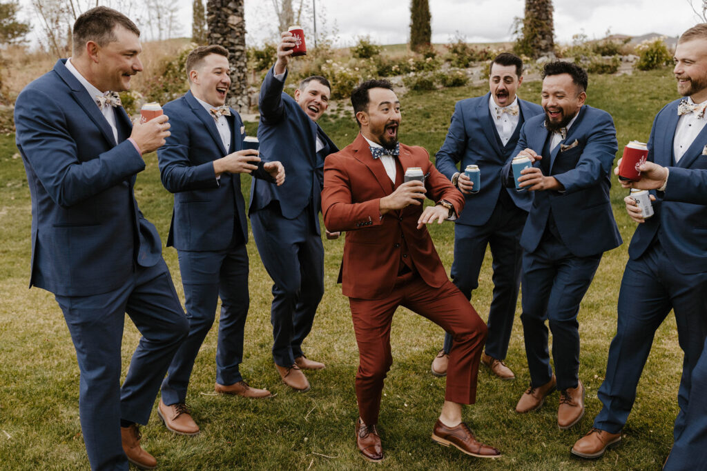 groomsmen laughing and drinking beers in navy suits