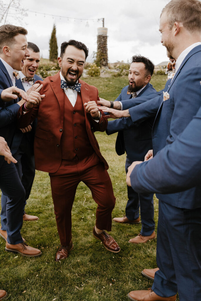 groomsmen laughing in navy suits at tuscan falls wedding
