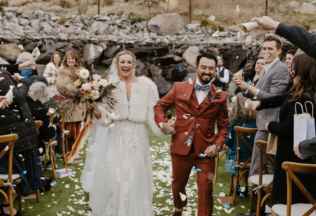 newlyweds exit their ceremony with flower petals falling on them