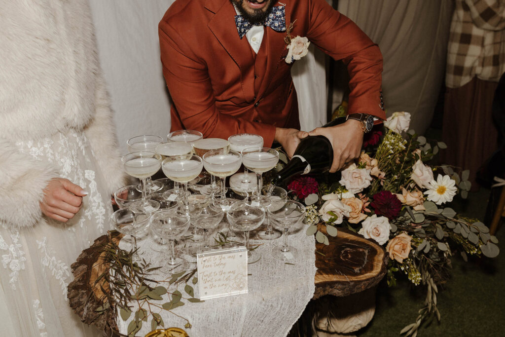 bride and groom pouring champagne into glasses at wedding reception