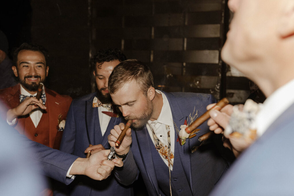 groom and groomsmen smoking cigars at tuscan falls wedding