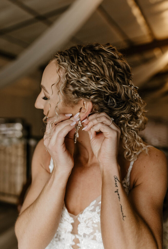 curly hair bride putting earrings in