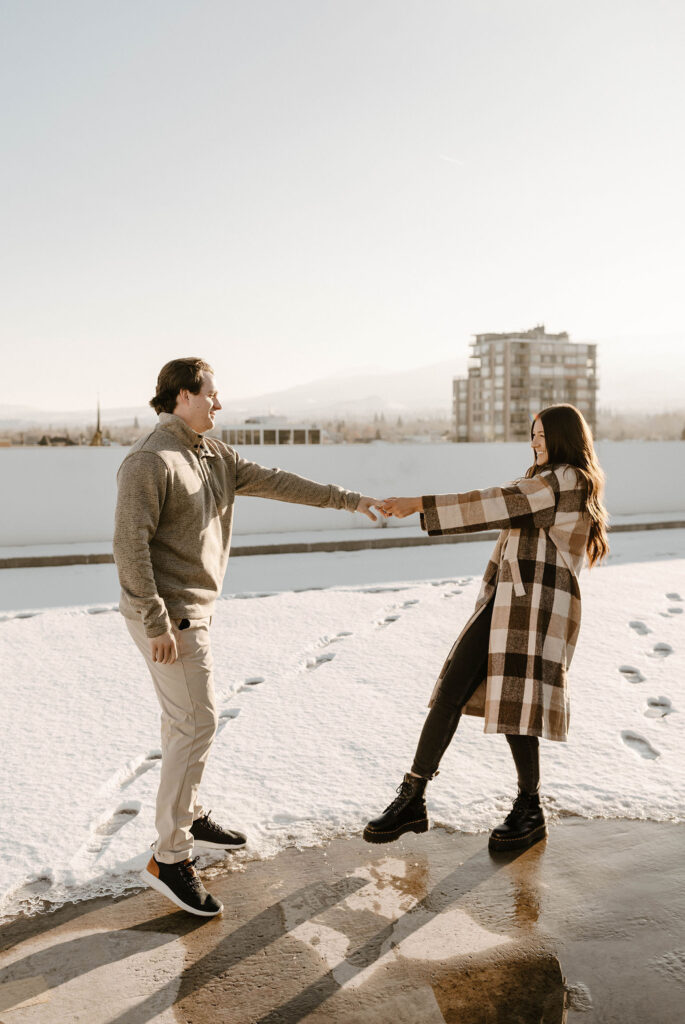 couple pulling on eachothers arms on a rooftop in reno in the winter