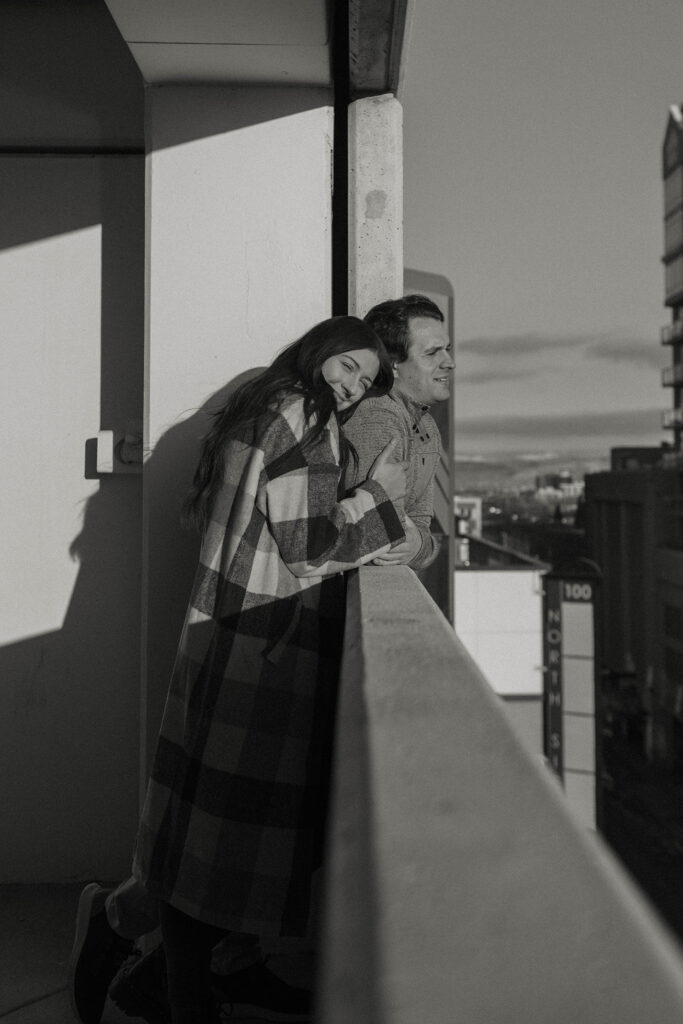 couple hugging against a ledge in downtown reno for their engagement photos