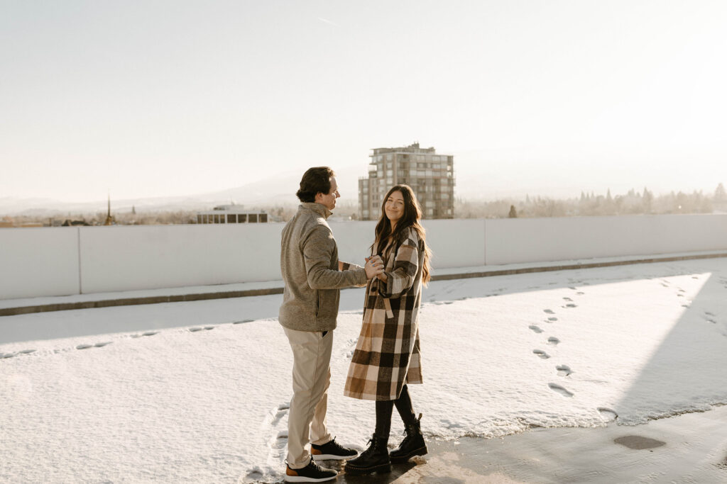 couple standing on a rooftop in the winter for their engagement photos