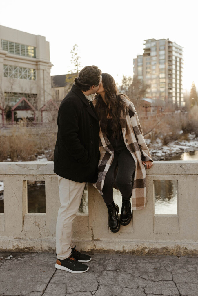 engagement couple sitting on a ledge by the river in downtown reno 