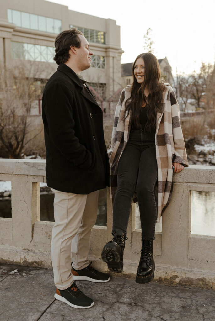 engagement couple sitting on a ledge by the river in downtown reno 