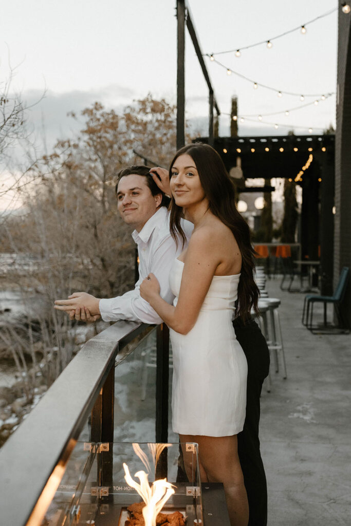 engagement couple standing next to a fire in nice clothing in downtown reno smiling