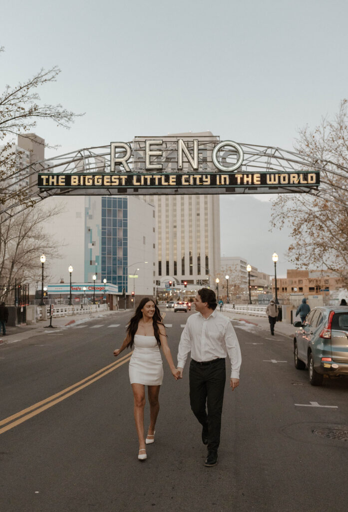engagement couple running under the reno sign