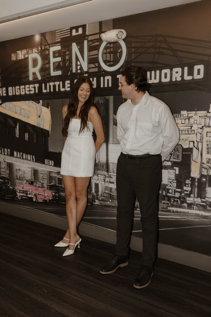 engagement couple leaning against a reno wall wearing nice clothing