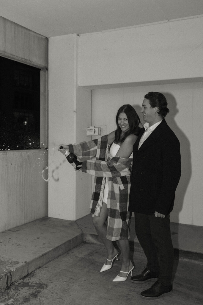 engagement couple popping champagne in a parking garage in reno