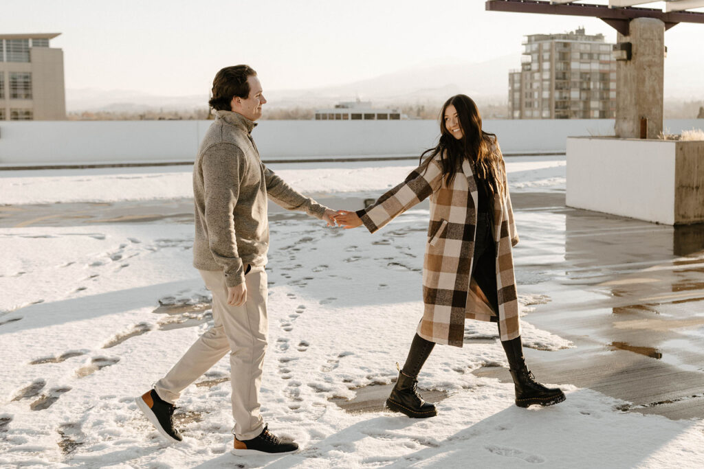 couple walking on a rooftop in the winter for their engagement photos