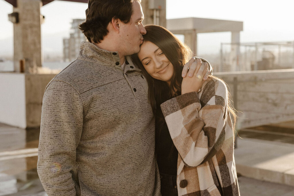 man kissing woman's forehead in downtown reno for their engagement photos