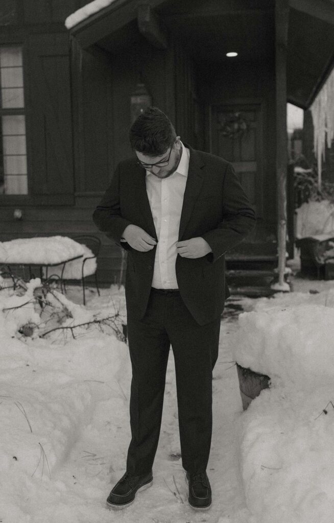 groom putting on his coat in the winter in lake tahoe