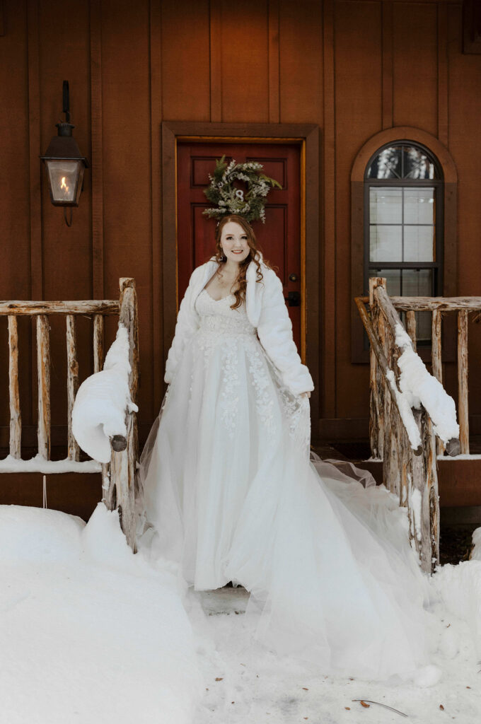bride smiling outside cabin steps smiling with snow on the ground