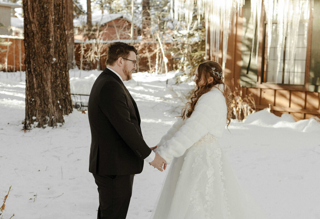 bride and groom smiling at each other and stand in the snow in lake tahoe