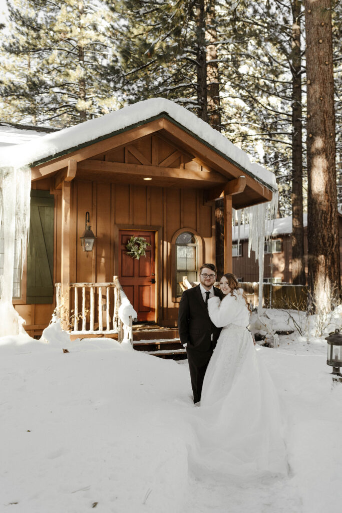 elopement couple standing in front of a cabin in the snow in lake tahoe