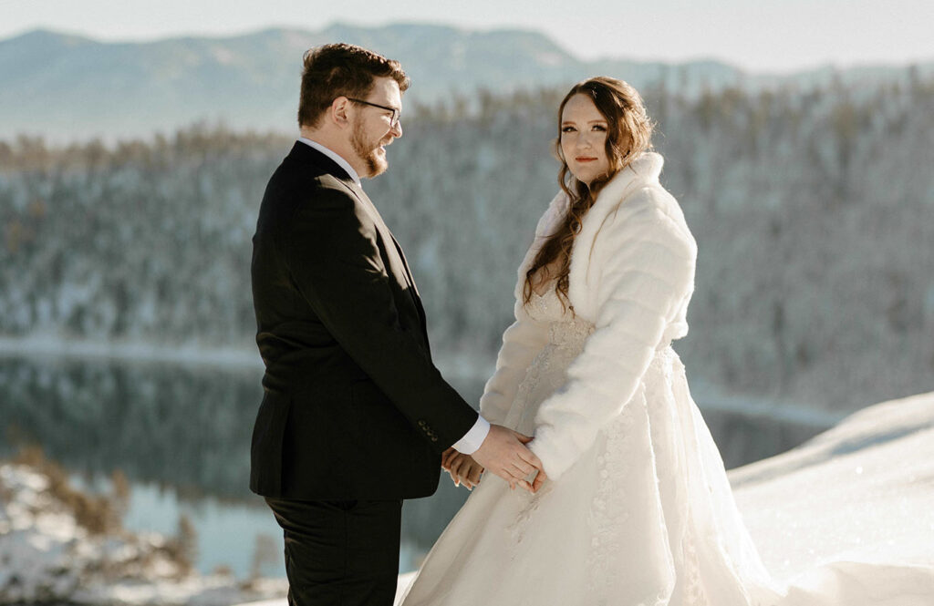 elopement couple holding hands while bride smiles at the camera in lake tahoe