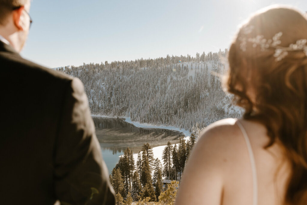 bride and groom blurry looking at lake tahoe below them in focus in the winter