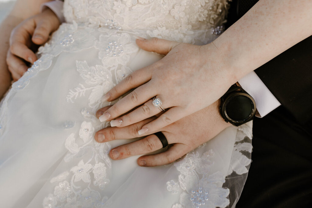 bride and groom holding hands and showing rings