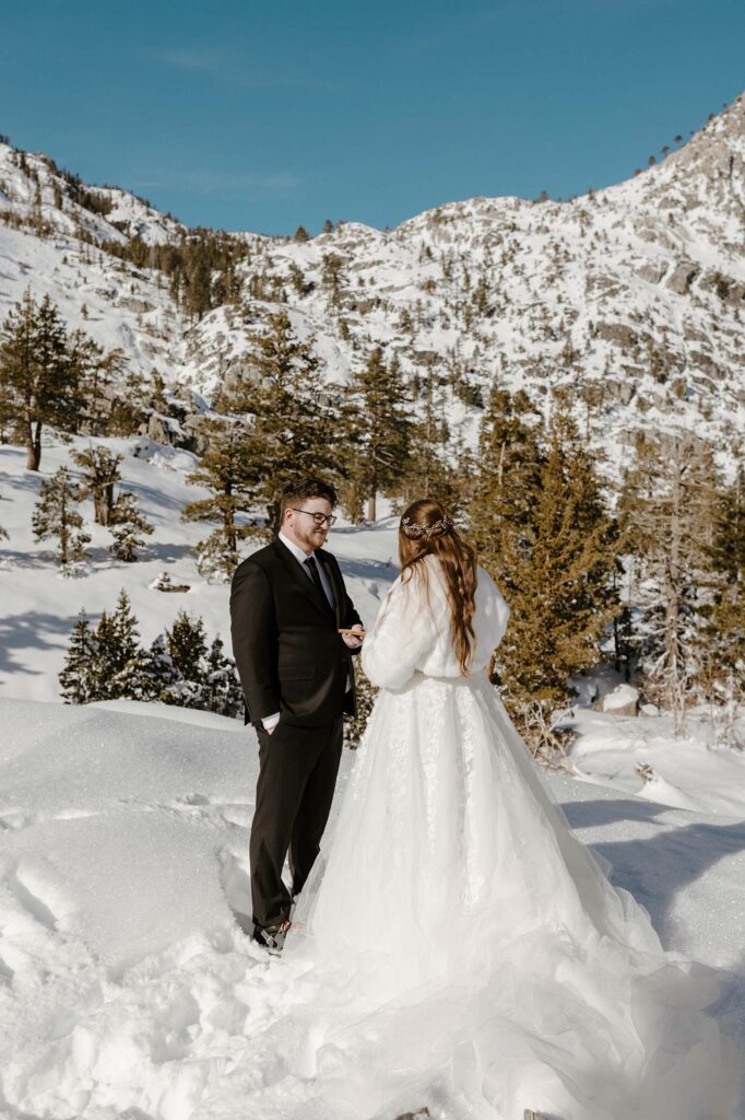 elopement couple sharing vows in the snow in lake tahoe while the groom smiles
