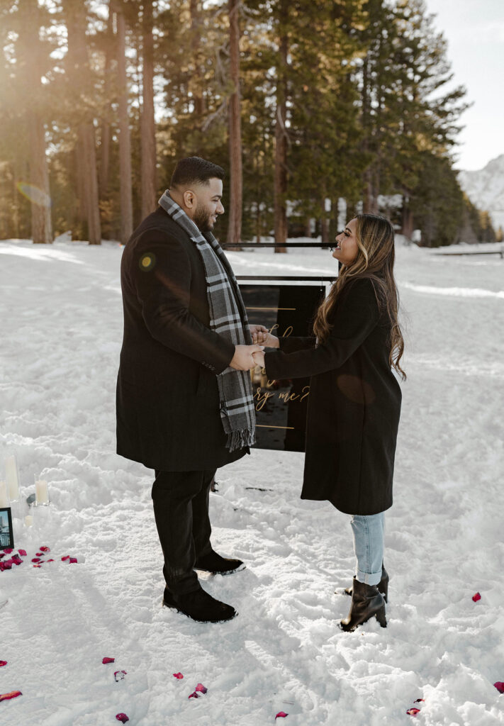 couple holding hands as man is proposing in south lake tahoe in the winter